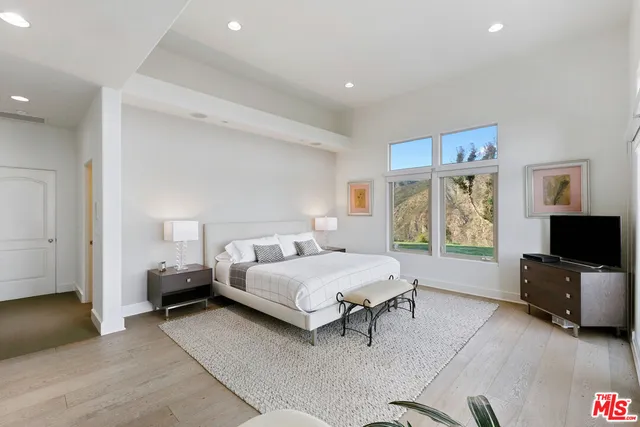 a bedroom with a bed a large window and flat screen tv