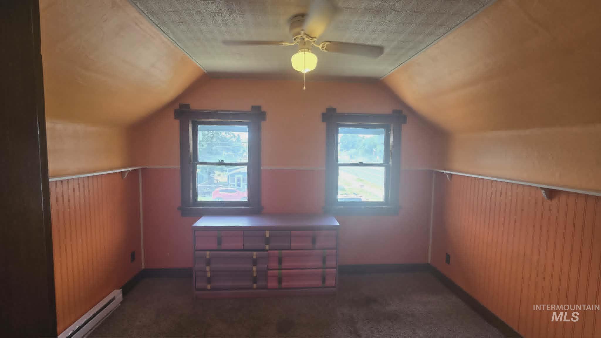 1212 Main Street Pomeroy, WA 99347 - Photo 15 of 18 Room with sloped ceilings, two windows with dark trim, ceiling fan, and wall-mounted baseboard heating