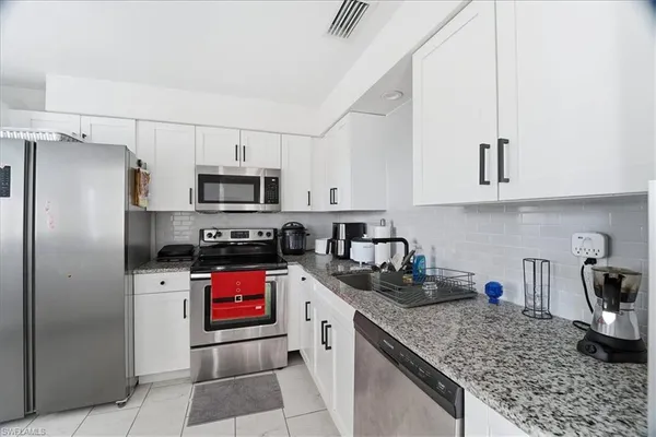 a kitchen with stainless steel appliances granite countertop a refrigerator and a stove top oven