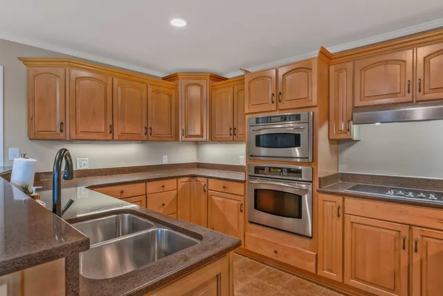 a kitchen with stainless steel appliances granite countertop a refrigerator stove top oven and sink