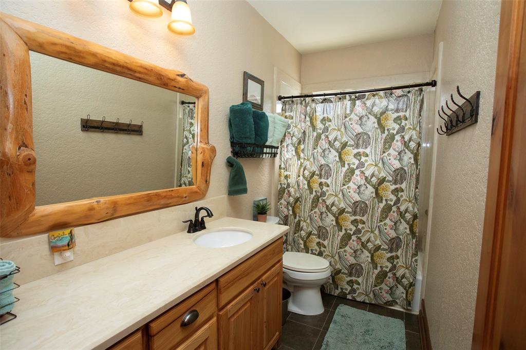 880 Cliffs Drive Graford, TX 76449 - Photo 15 of 40 a bathroom with a granite countertop sink and a mirror