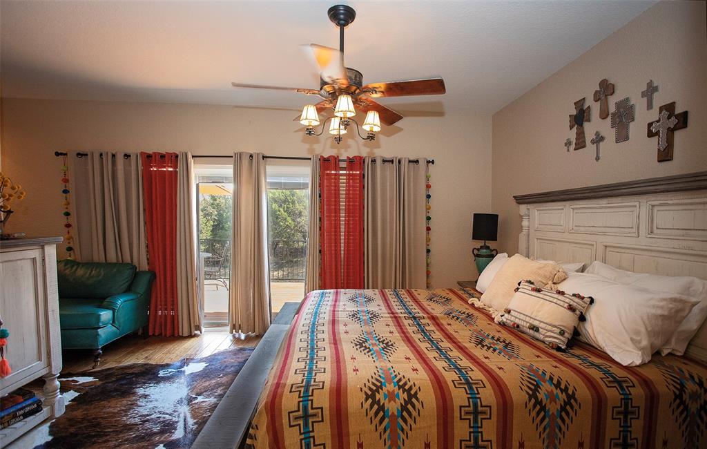 880 Cliffs Drive Graford, TX 76449 - Photo 20 of 40 a bedroom with a large bed a chandelier and a window