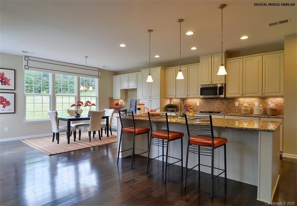 7123 Messina Road, Unit 130 Indian Land, SC 29707 - Photo 2 of 15 a open kitchen with stainless steel appliances granite countertop a stove top oven a sink a dining table and chairs with wooden floor