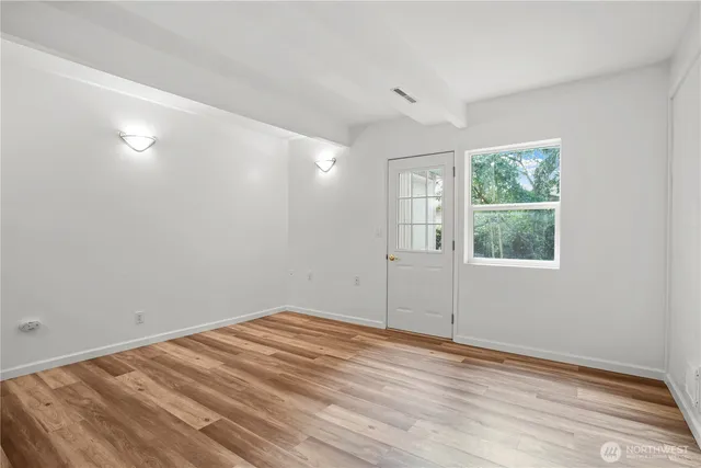 an empty room with wooden floor and windows