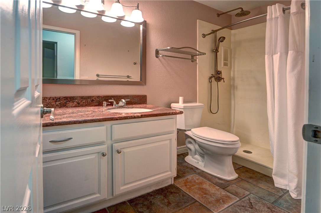 2108 Crestpoint Way Las Vegas, NV 89134 - Photo 19 of 27 A well-appointed bathroom features a single vanity with a granite countertop and a practical shower-over-toilet layout.