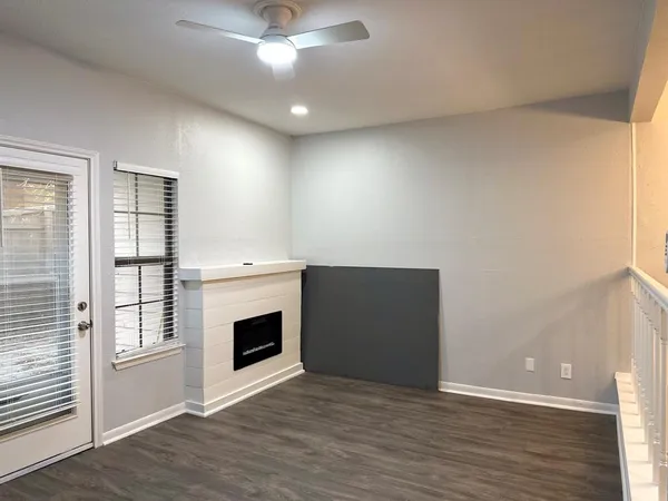 an empty room with wooden floor fireplace and windows