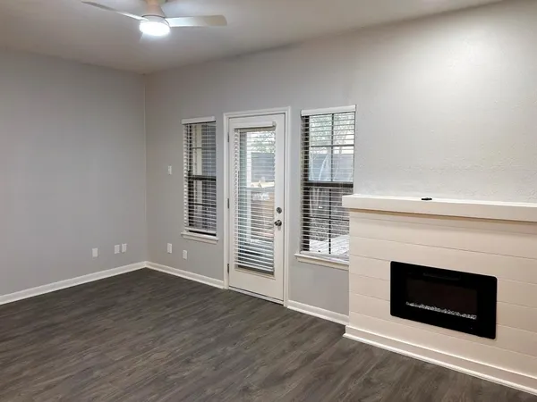 an empty room with wooden floor fireplace and windows