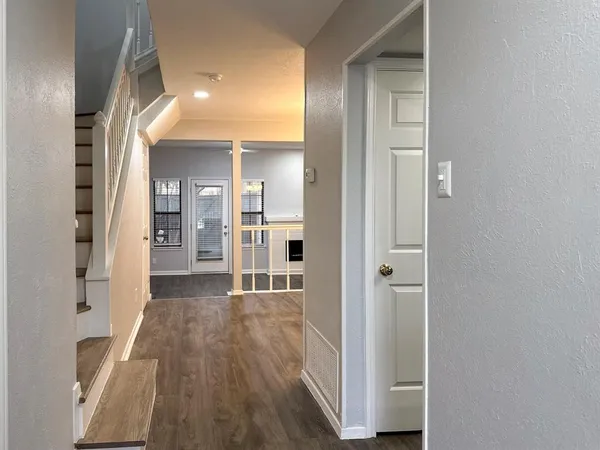 a view of a hallway with wooden floor and a living room