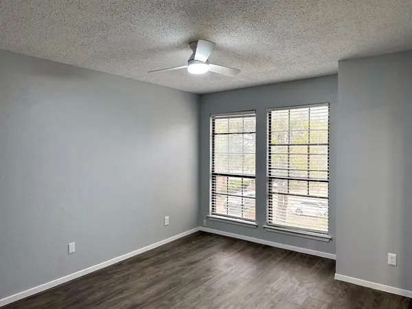 an empty room with wooden floor chandelier and windows