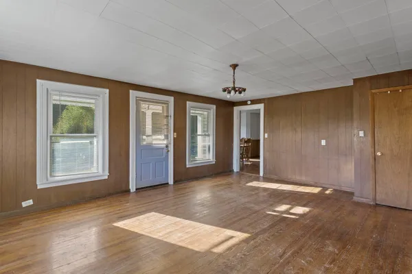 a view of an empty room with window and wooden floor
