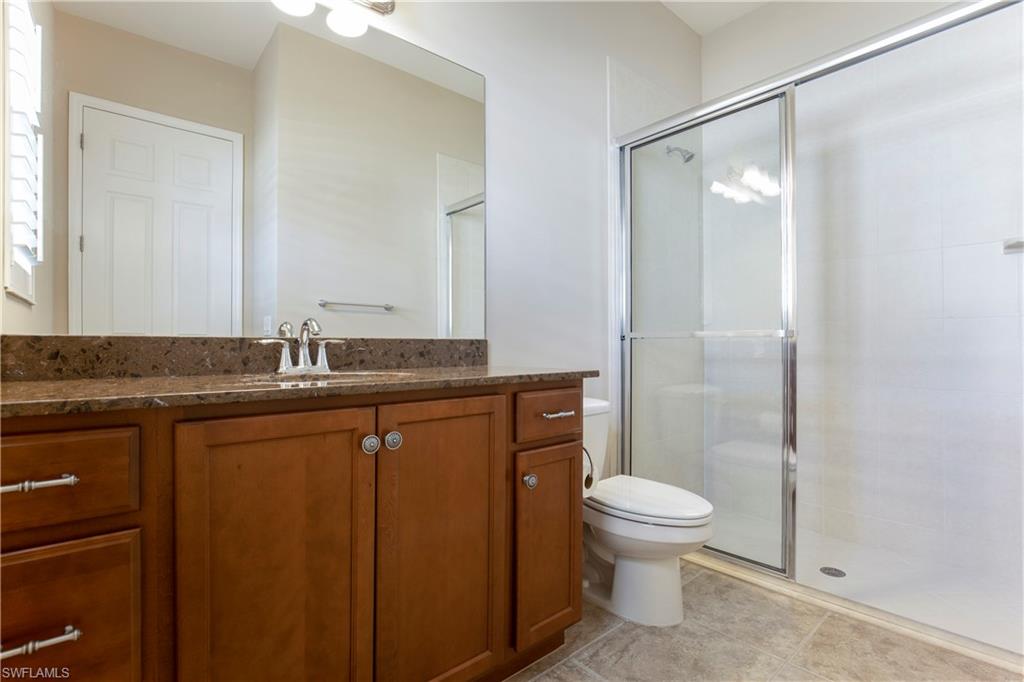 13515 Cambridge Lane Naples, FL 34109 - Photo 17 of 28 a bathroom with a granite countertop sink toilet and shower