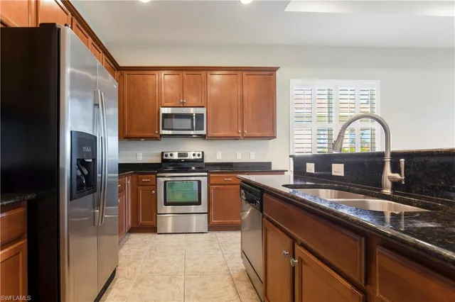 a kitchen with granite countertop a sink stainless steel appliances and cabinets