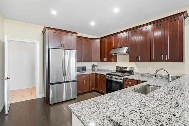 a kitchen with granite countertop stainless steel appliances a refrigerator and a sink