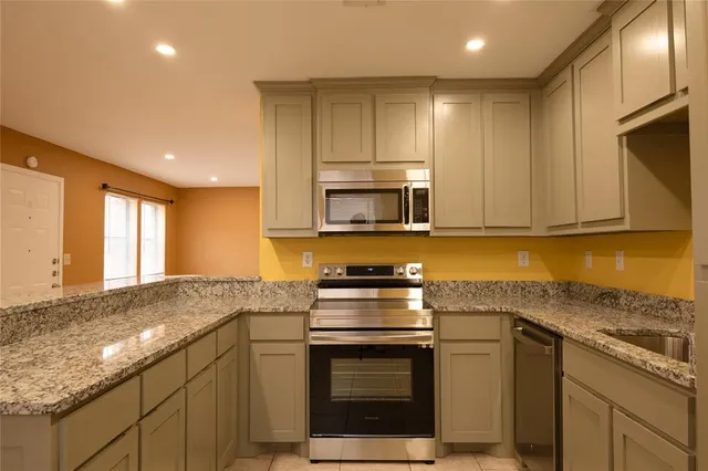 a kitchen with granite countertop white cabinets stainless steel appliances and a sink