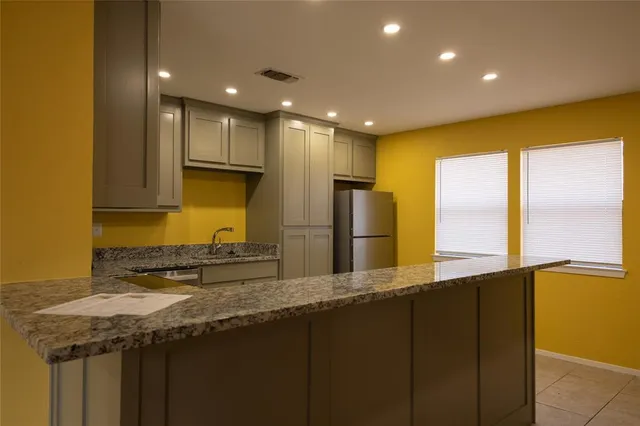 a kitchen with stainless steel appliances granite countertop a sink a refrigerator and a stove top oven