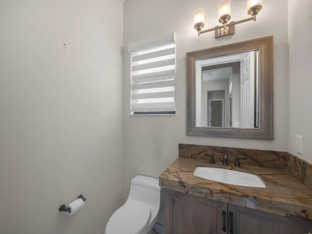 a bathroom with a granite countertop toilet sink and mirror