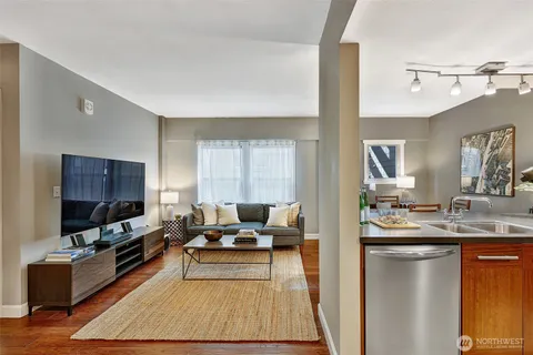 a living room with stainless steel appliances kitchen island granite countertop a couch and a flat screen tv