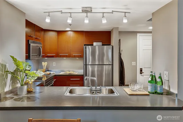 a kitchen with kitchen island granite countertop a sink stainless steel appliances and cabinets