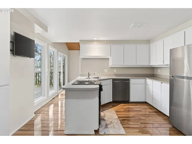 a kitchen with stainless steel appliances kitchen island granite countertop a refrigerator a sink dishwasher and a stove with wooden floor