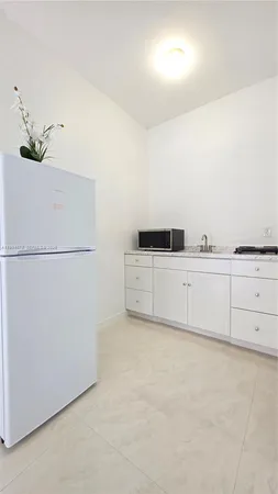 a kitchen with white cabinets and white refrigerator