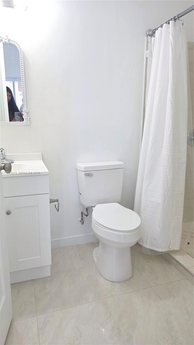 14552 Southwest 158th Court Miami, FL 33196 - Photo 20 of 21 a white toilet sitting next to a white sink a shower curtain