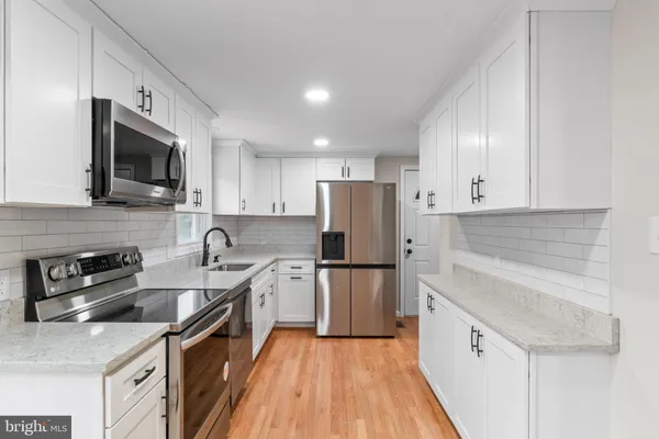 a kitchen with a sink a refrigerator a microwave and cabinets
