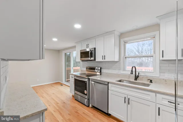 a kitchen with stainless steel appliances granite countertop a sink dishwasher stove and microwave with wooden floor