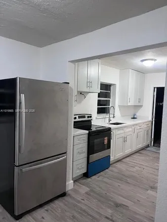 a kitchen with a refrigerator stove and wooden floors