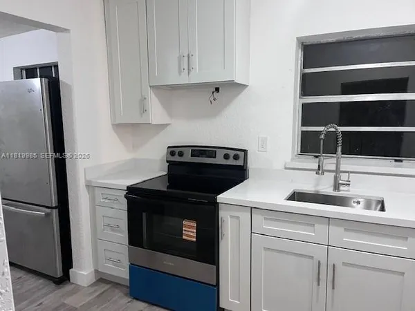 a kitchen with white cabinets and a refrigerator with wooden floor