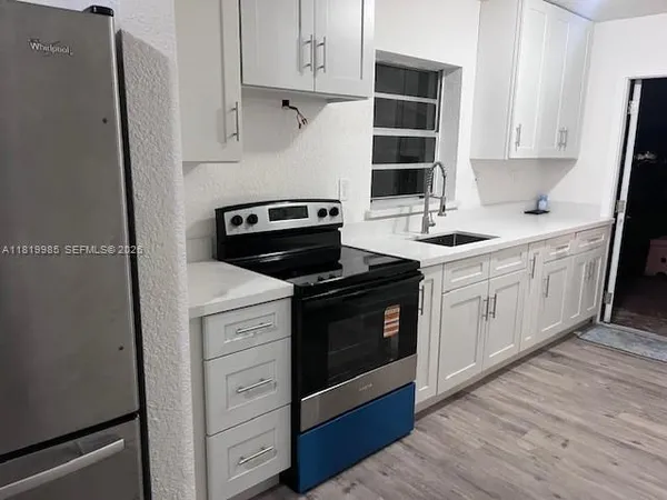 a kitchen with cabinets appliances and wooden floor
