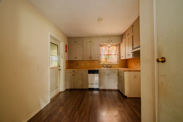 a kitchen with white cabinets and wooden floor