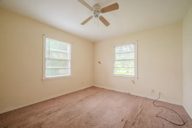 an empty room with a window and a ceiling fan