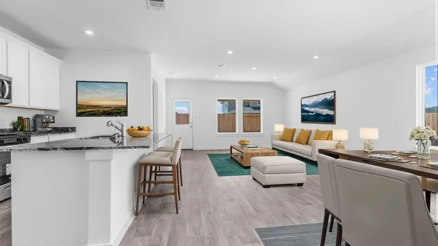 a living room with granite countertop couches a coffee table and kitchen view with wooden floor