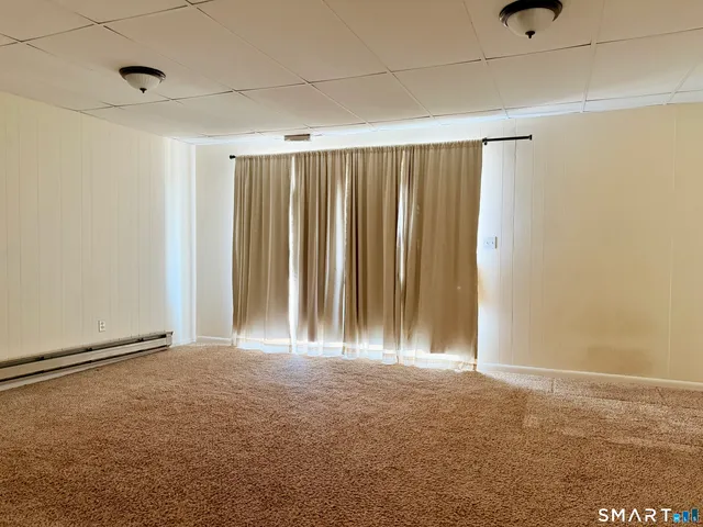 a view of a refrigerator in kitchen and an empty room with wooden floor