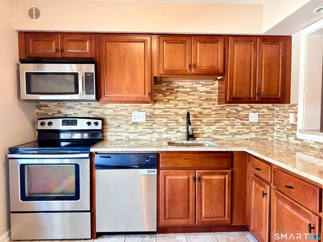 a kitchen with stainless steel appliances granite countertop wooden cabinets and a stove top oven