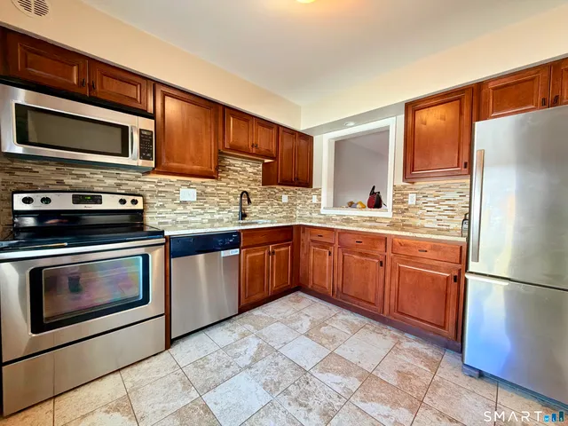 a kitchen with stainless steel appliances granite countertop a refrigerator stove top oven and sink