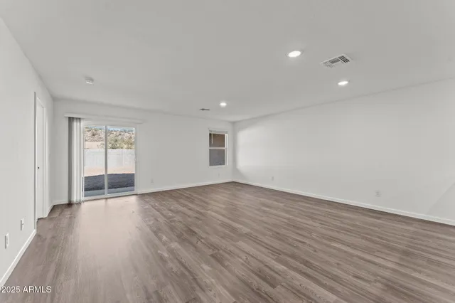 a view of an empty room with wooden floor and windows