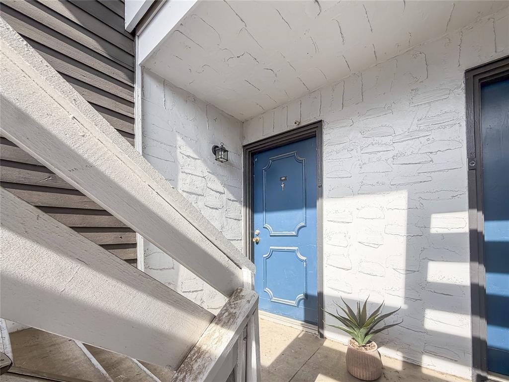 5840 Spring Valley Road, Unit 1104 Dallas, TX 75254 - Photo 2 of 16 Entryway featuring a blue paneled door, exterior wall lantern, and textured stucco finish