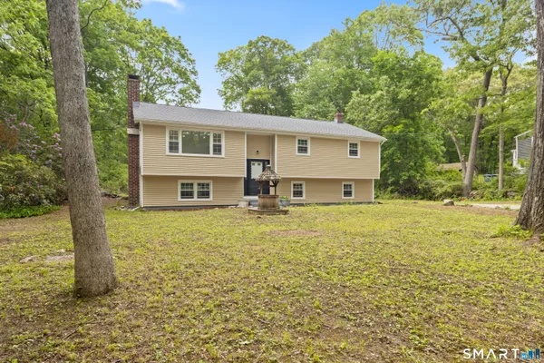 a front view of house with yard and trees in the background