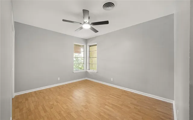 an empty room with a window and a fan