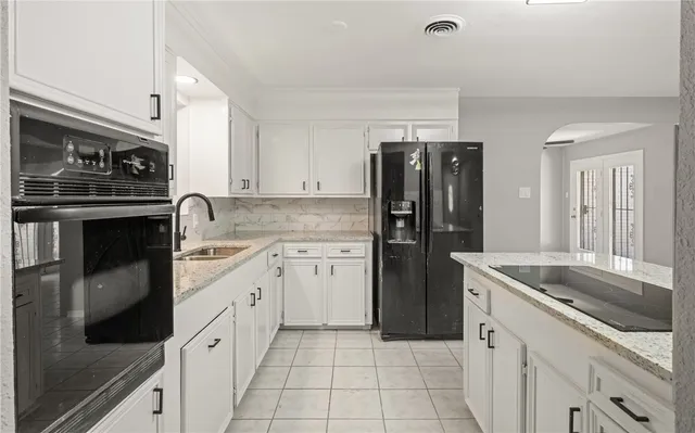 a kitchen with granite countertop a sink stove and refrigerator