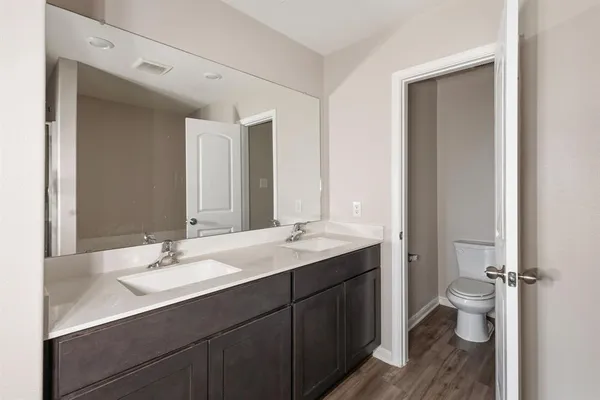 a bathroom with a double vanity sink toilet and mirror