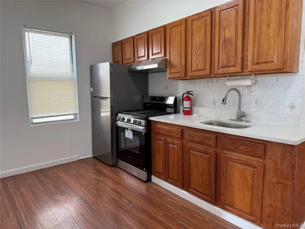 a kitchen with granite countertop wooden floors wooden cabinets and stainless steel appliances