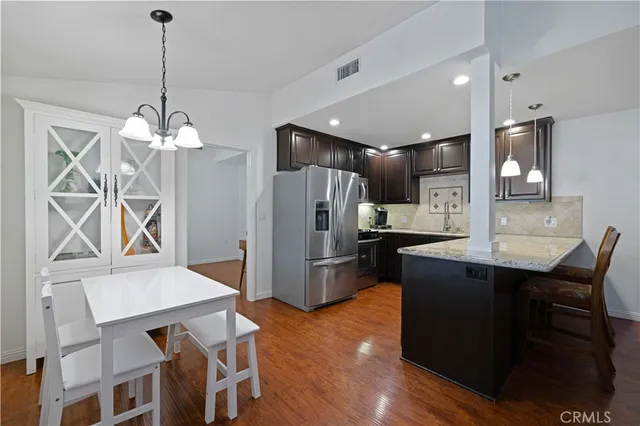 a kitchen with refrigerator a sink dishwasher a dining table and chairs with wooden floor