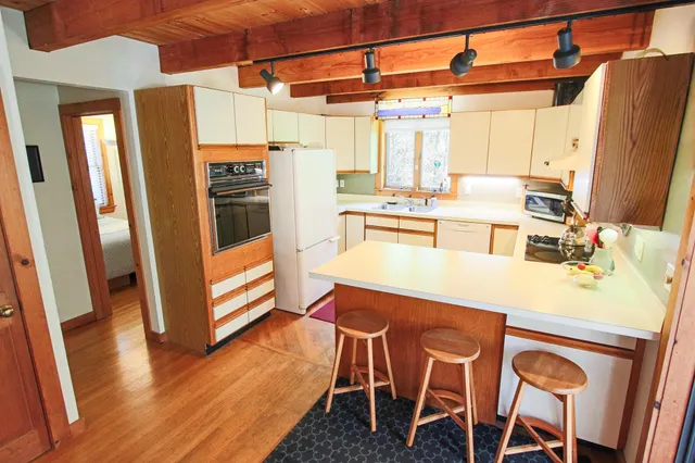 a kitchen with stainless steel appliances a dining table chairs and refrigerator