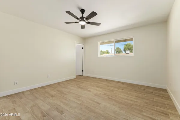 an empty room with wooden floor and ceiling fan