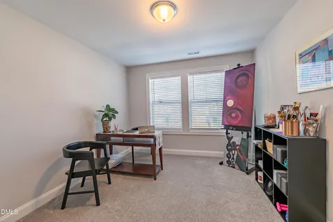 a work room with furniture a bookshelf and a window