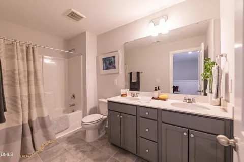 a spacious bathroom with a double vanity sink toilet mirror and shower
