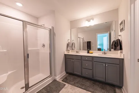 a bathroom with a double vanity sink and mirror with shower