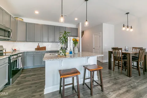 a kitchen with kitchen island a dining table chairs and white cabinets